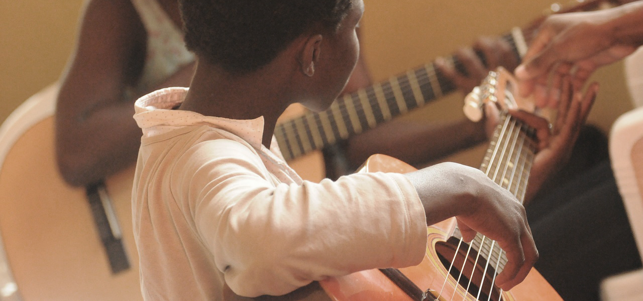Jeunes élèves qui jouent de la guitare lors du spectacle organisé par Musique O Max.