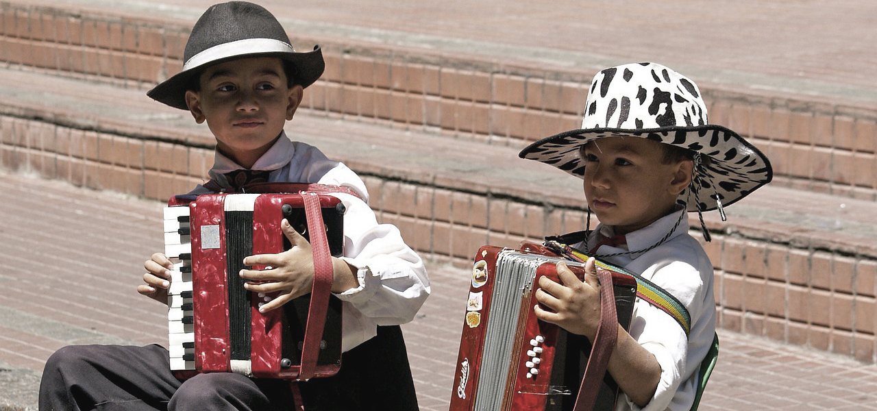 Jeune élève portant un grand chapeau au couleur d'une vache jouant de l'accordéon.
