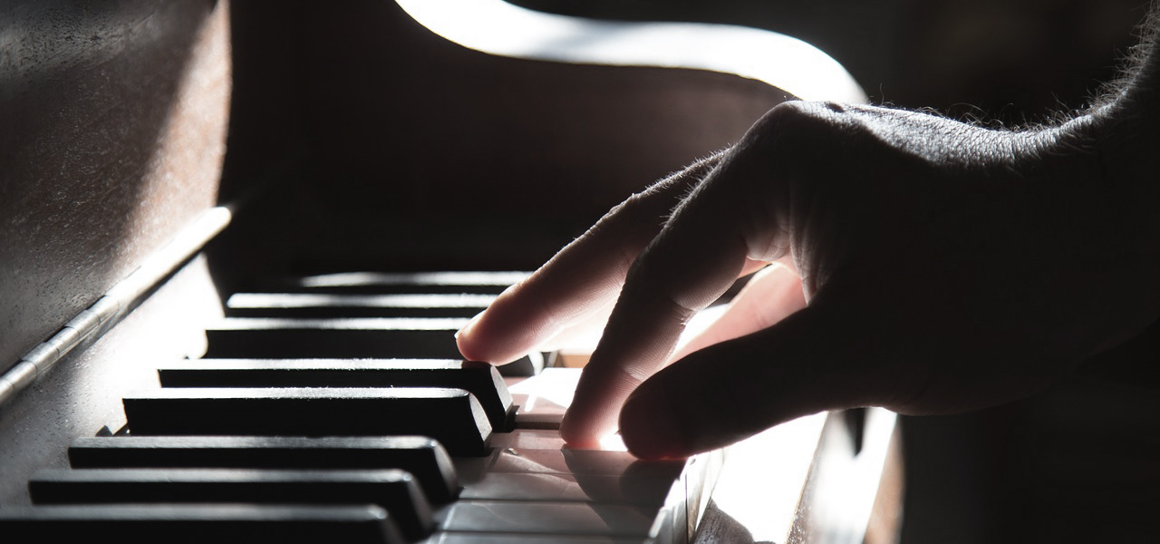 Gros plan sur les touches d'un piano avec la main d'une personne.