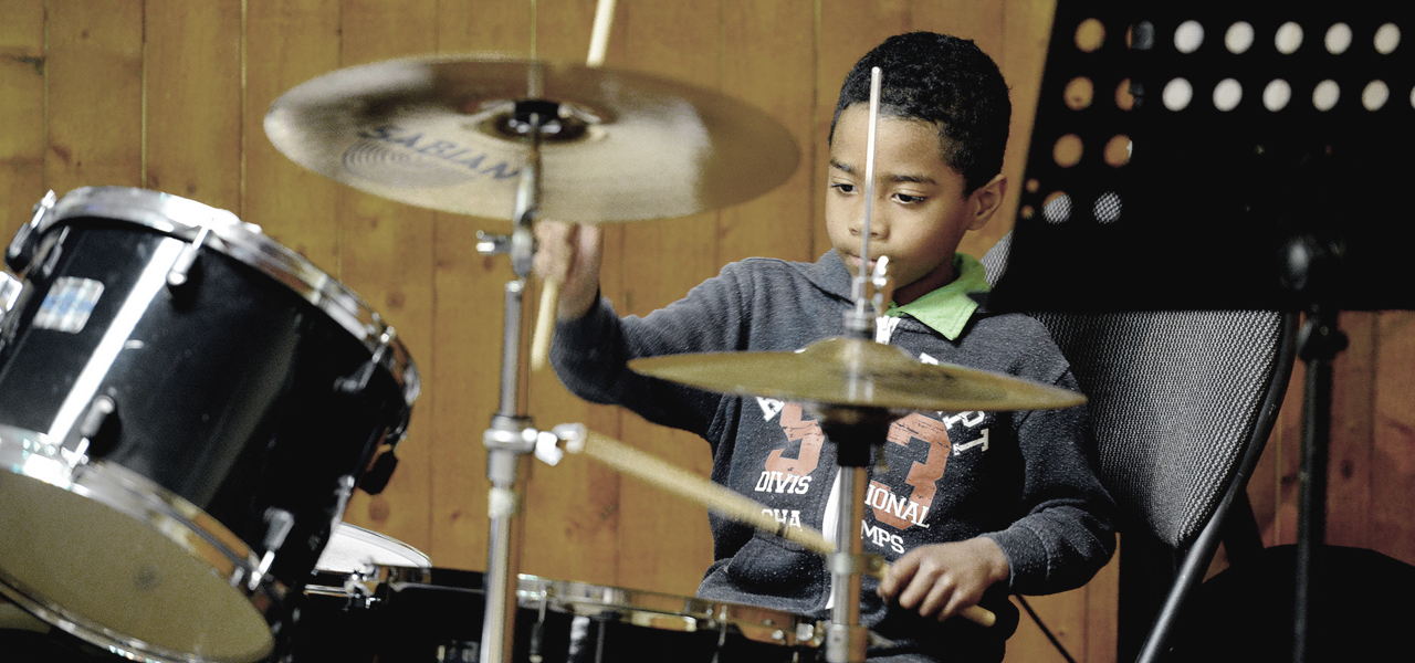 enfant de 10-12 ans jouant de la batterie lors du spectacle organisé par Musique O Max.